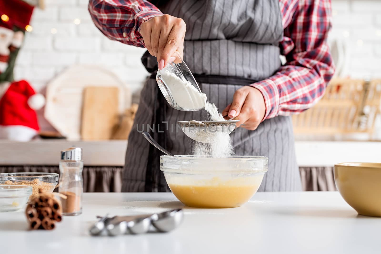 Young latin woman pouring flour to the dough cooking at the kitchen by Desperada