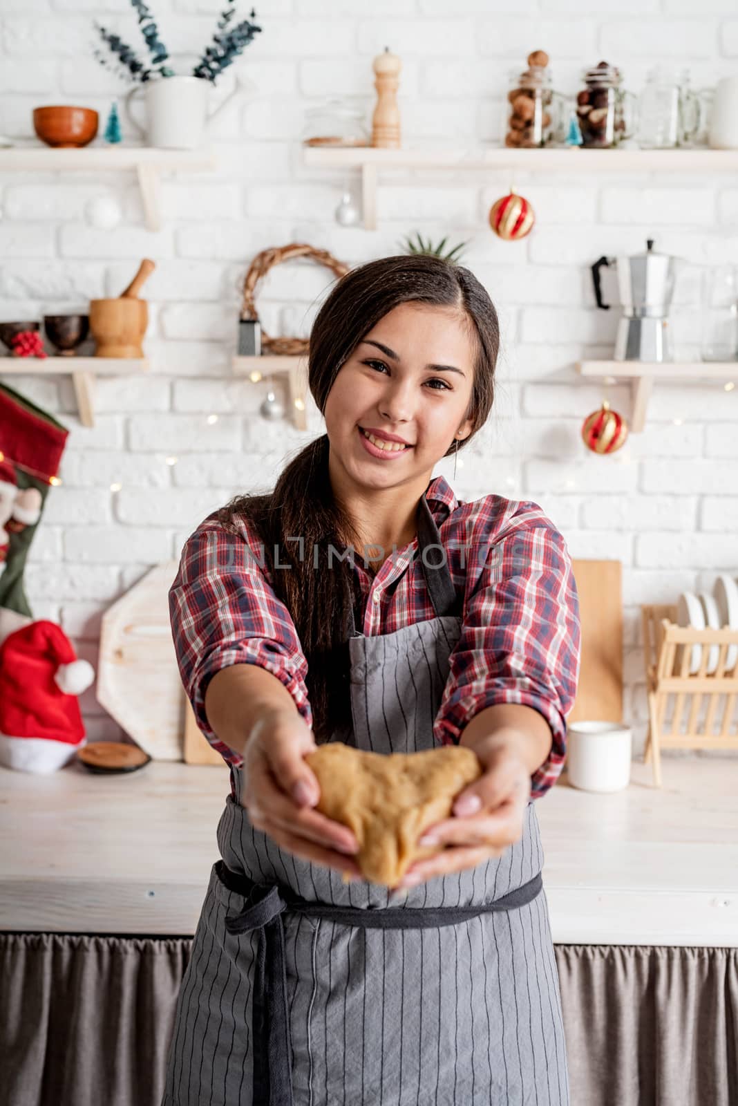 Cooking and baking. Happy brunette woman holding heart shaped dough at the kitchen