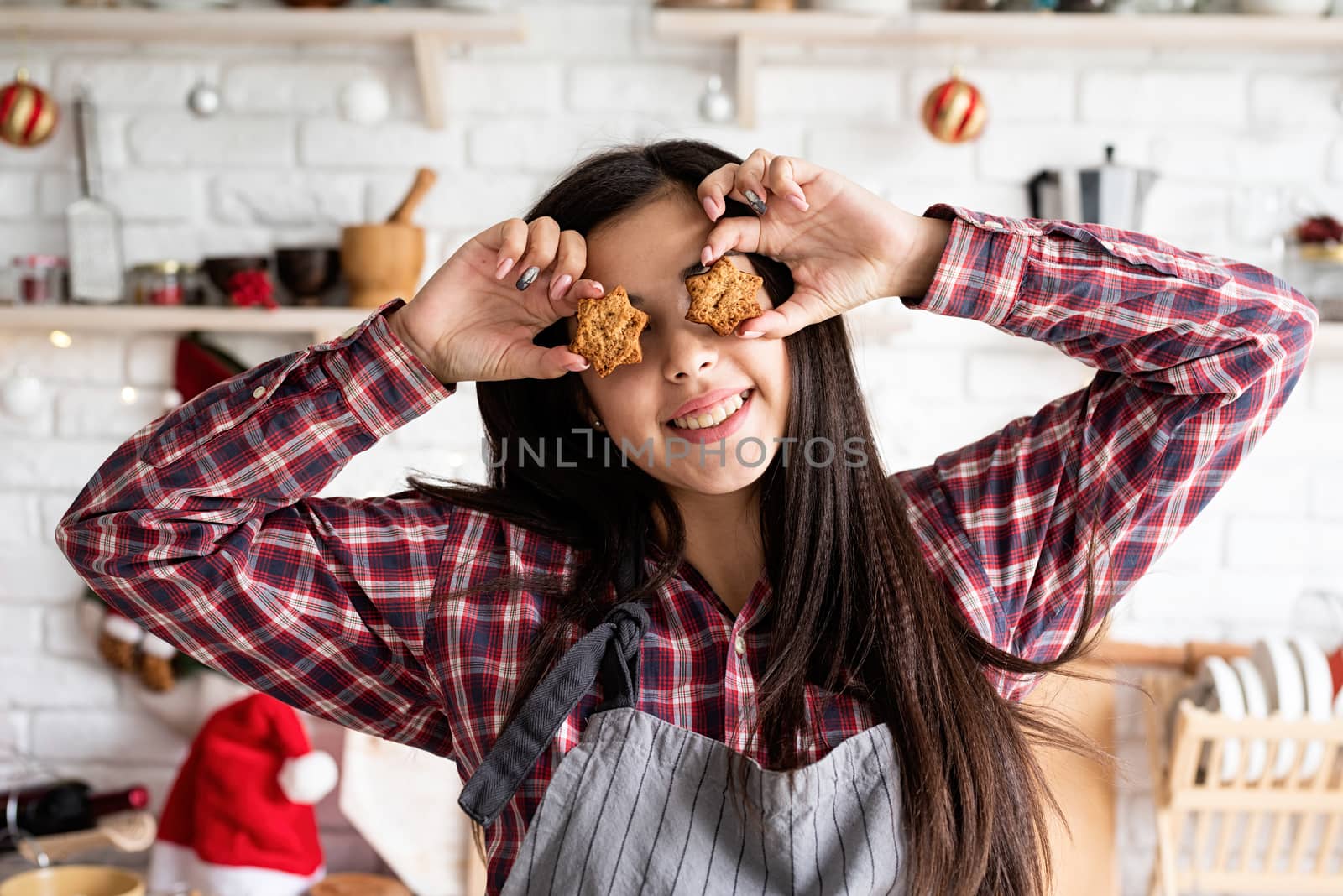 Cooking and baking. Happy woman in apron holding star shaped cookies in front of her eyes