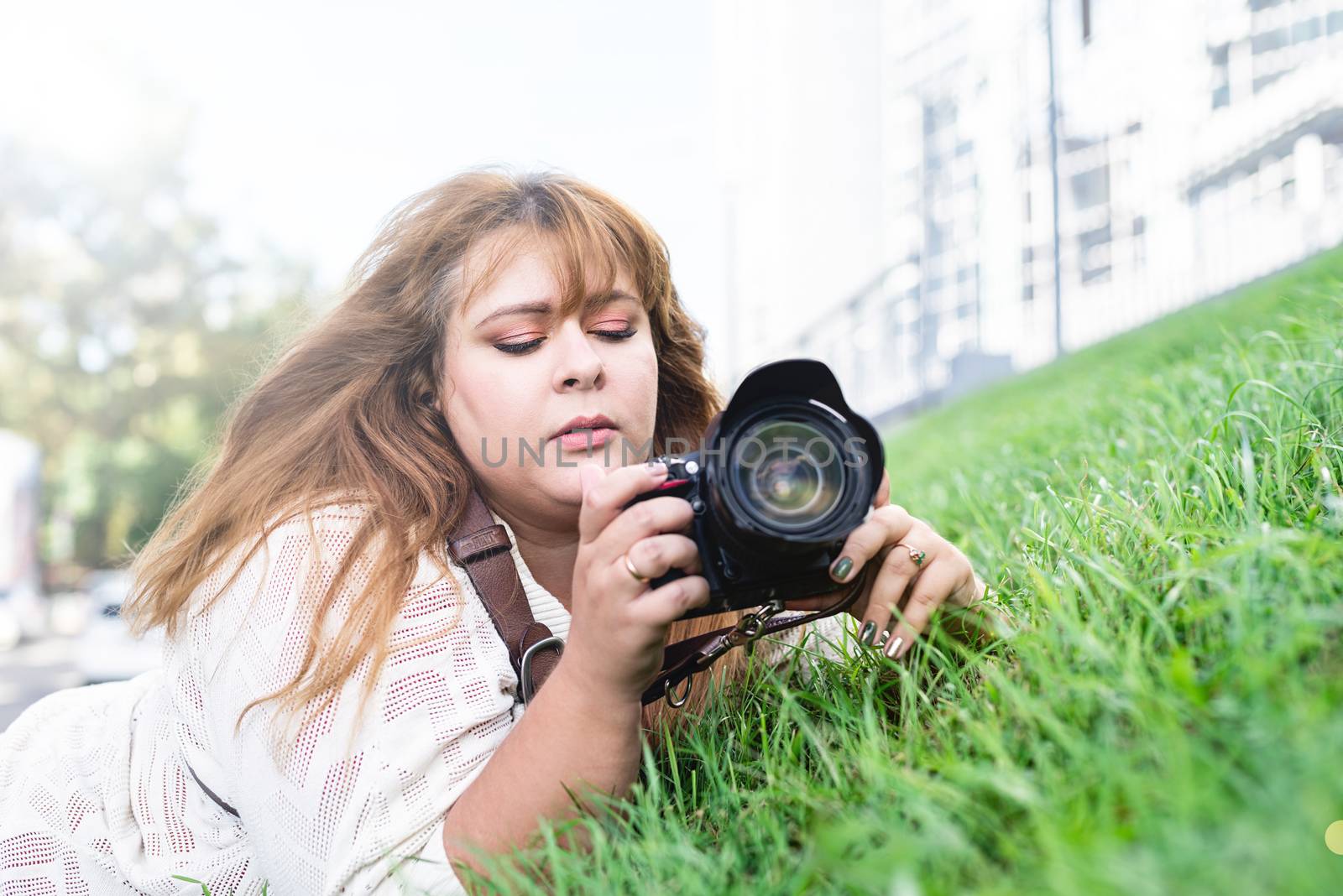 Portrait of overweight woman taking pictures with a camera in the park by Desperada