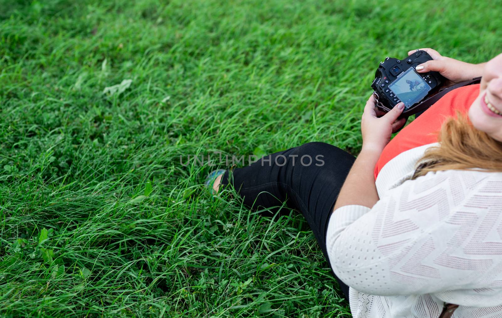 Body positive. Portrait of overweight woman taking pictures with a camera in the park