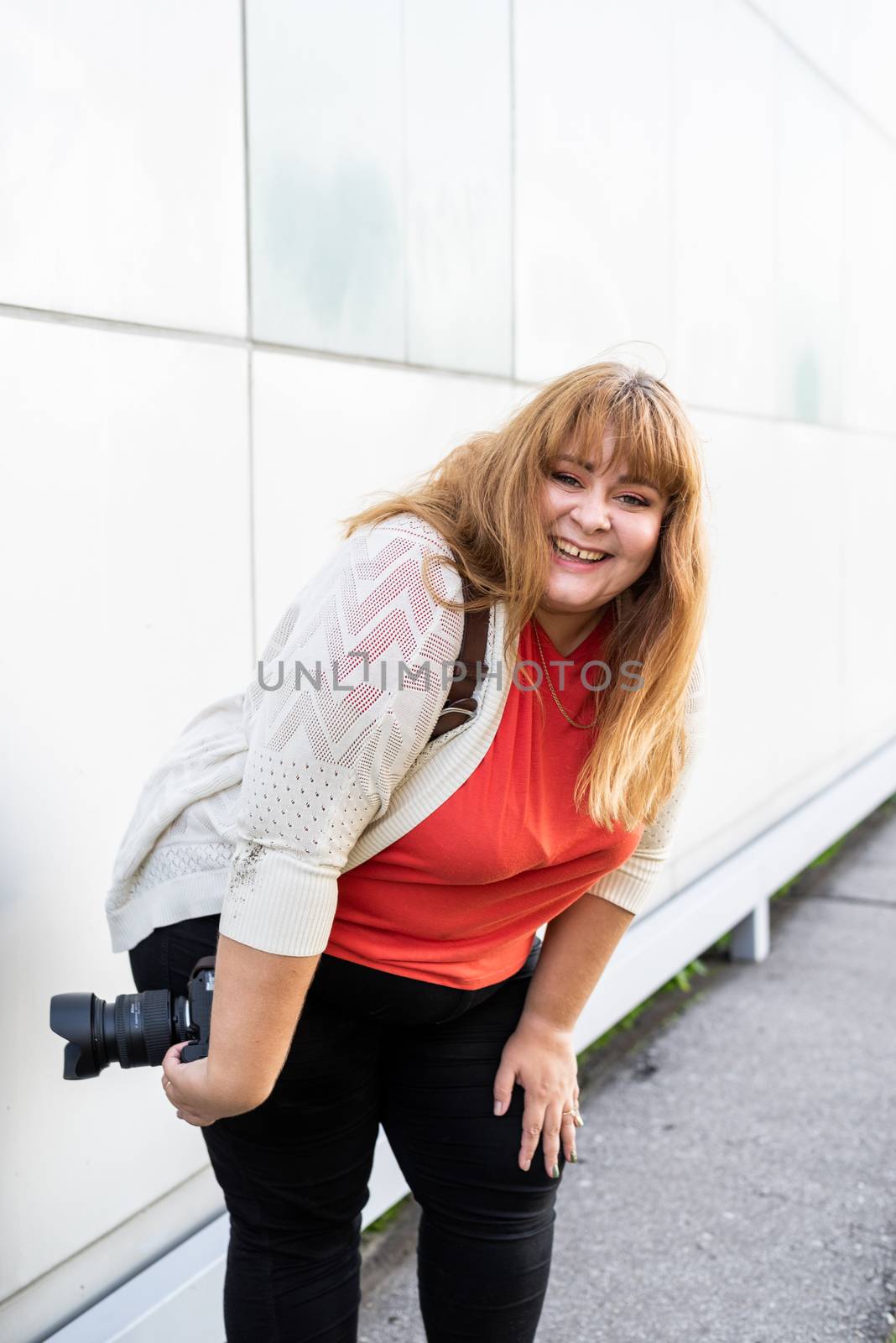 Portrait of overweight woman taking pictures with a camera outdoors by Desperada
