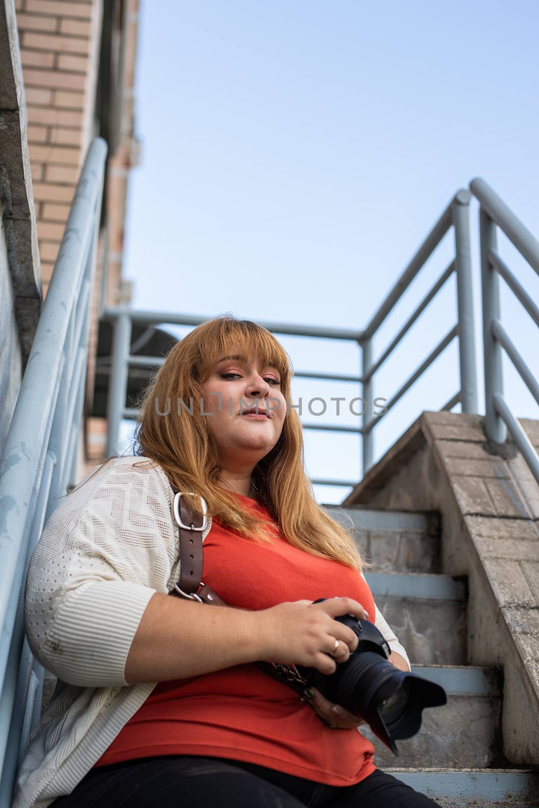 Portrait of overweight woman taking pictures with a camera outdoors by Desperada