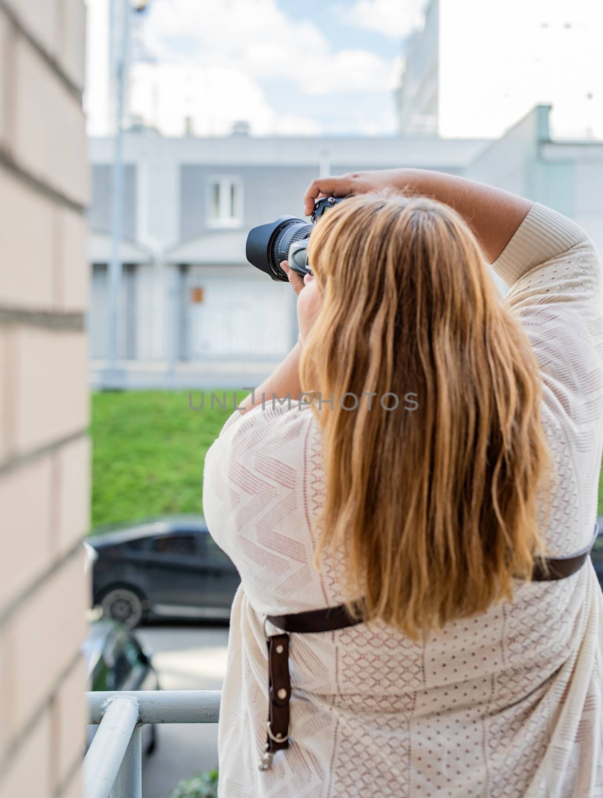 Body positive. Portrait of overweight woman taking pictures with a camera outdoors