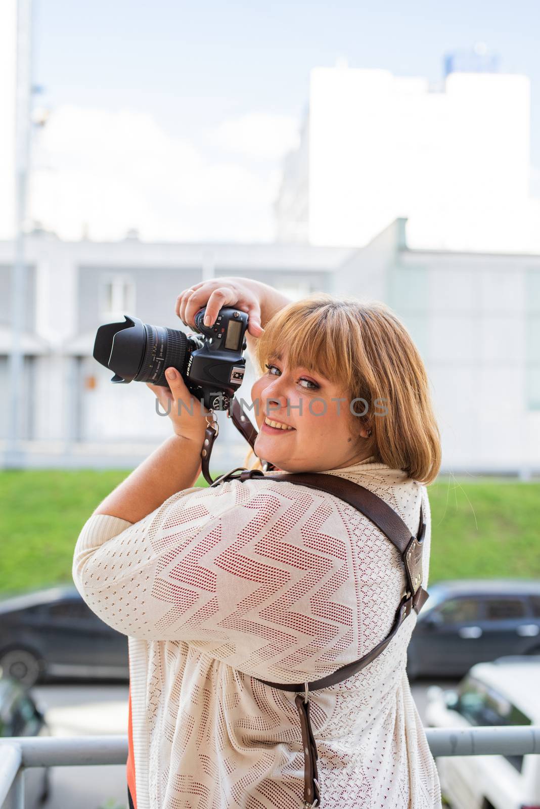 Body positive. Portrait of overweight woman taking pictures with a camera outdoors