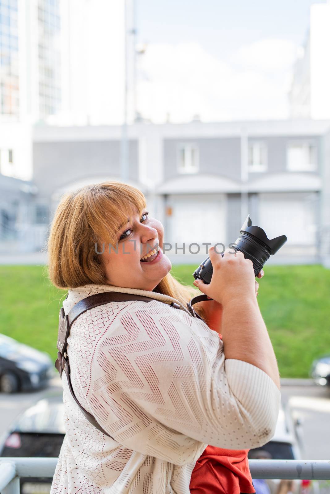 Portrait of overweight woman taking pictures with a camera outdoors by Desperada