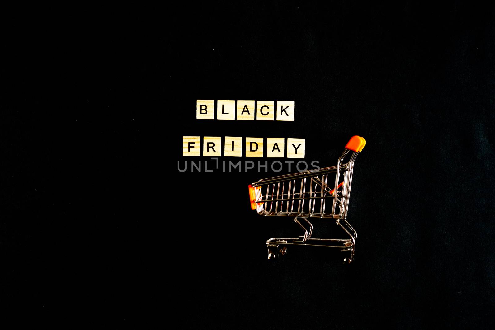 Black Friday written in wooden letters on a black background with a shopping basket, sales, holiday sales, top view, flat layout, price reduction by Pirlik