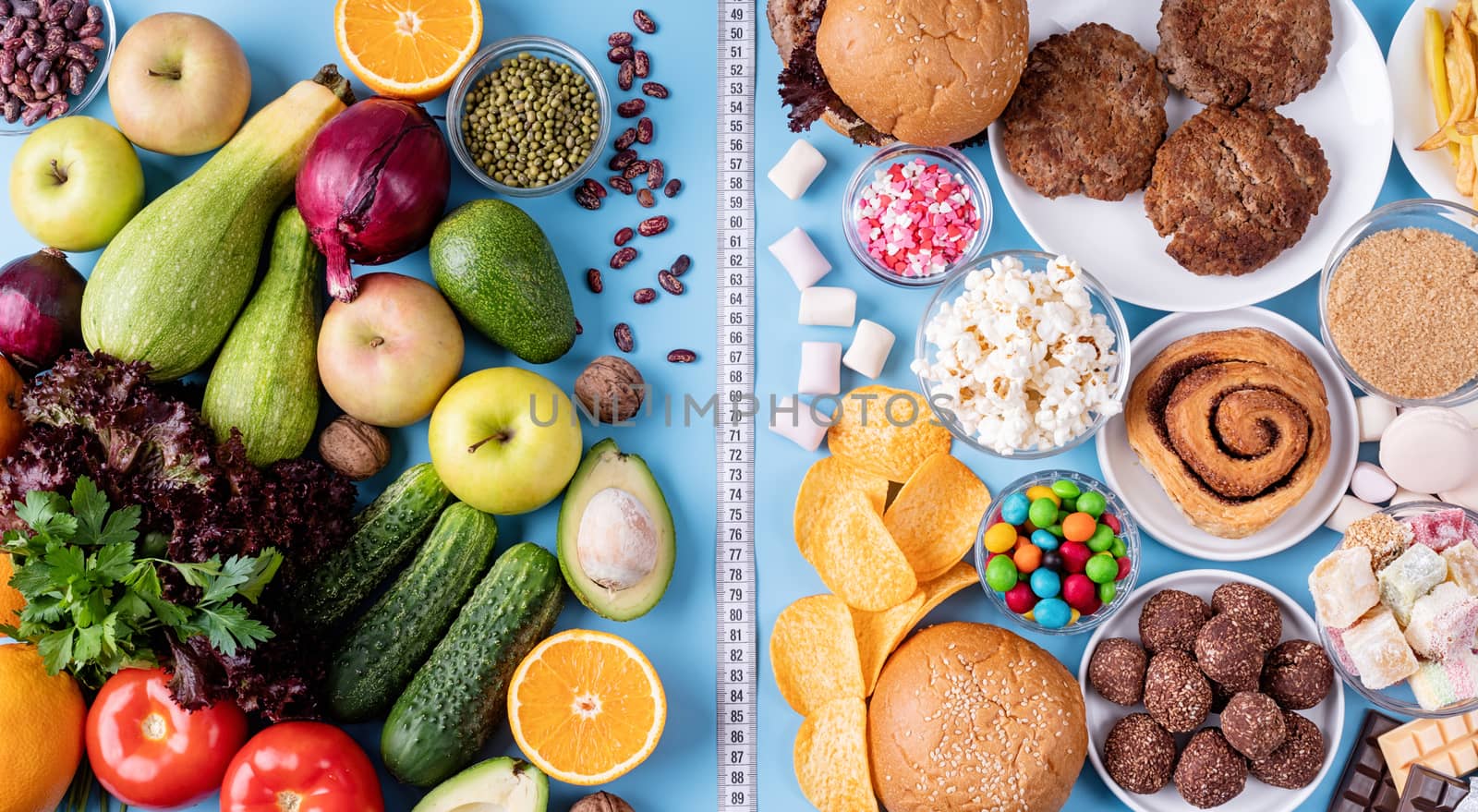 Healthy and unhealthy food concept. Fruit and vegetables vs sweets and fast food top view flat lay on blue background