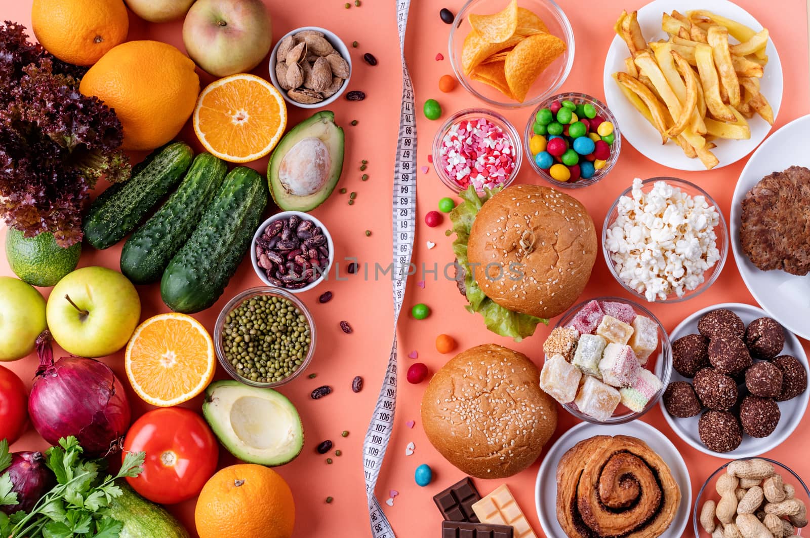 Healthy and unhealthy food concept. Fruit and vegetables vs sweets and fast food top view flat lay on orange background