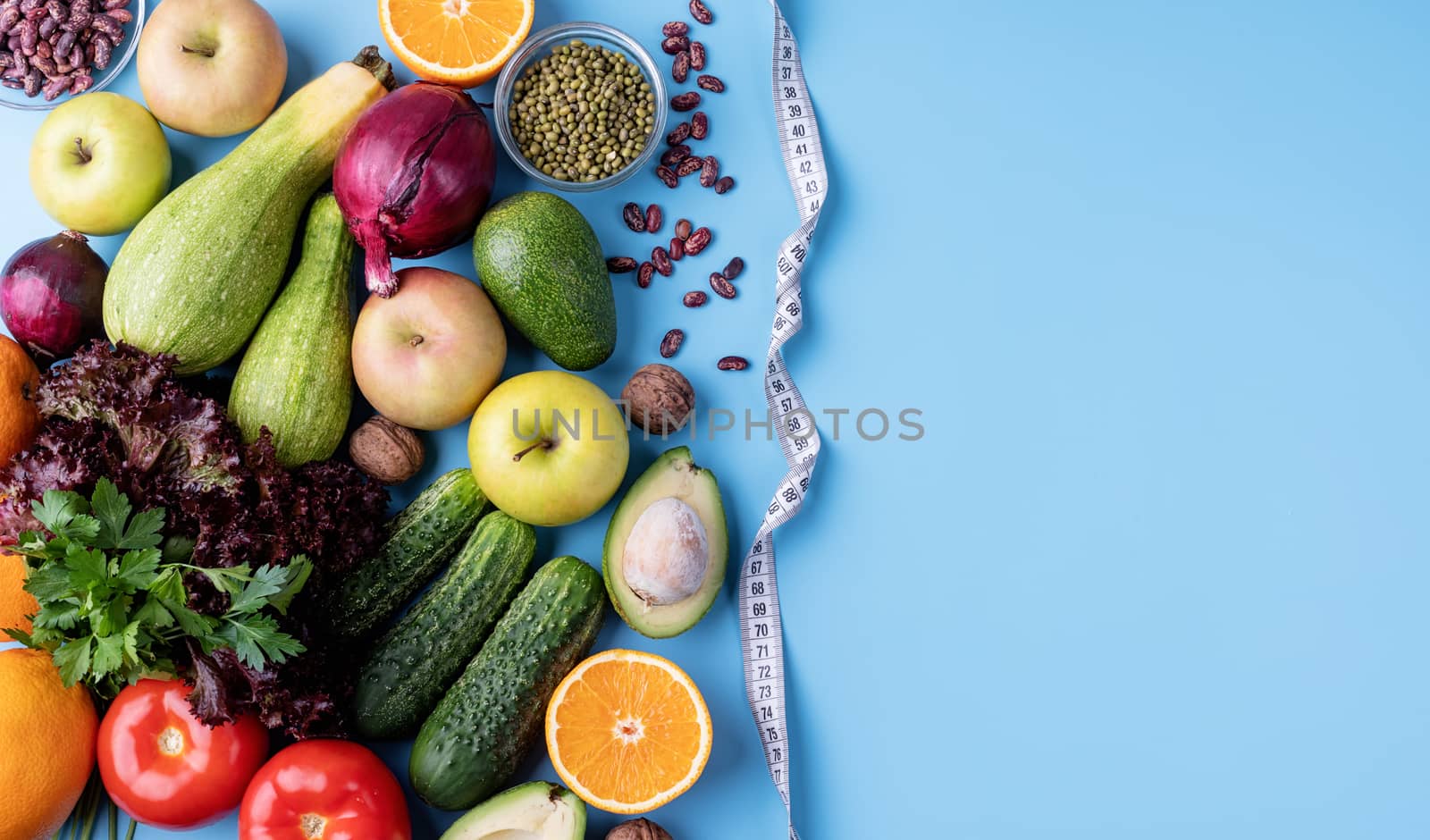 Healthy diet. Fresh vegetables and fruit for healthy diet and a measuring tape top view flat lay on blue background with copy space