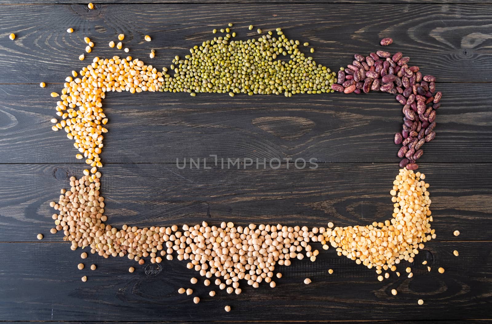 Various dried legumes forming a frame top view flat lay on black wooden background by Desperada