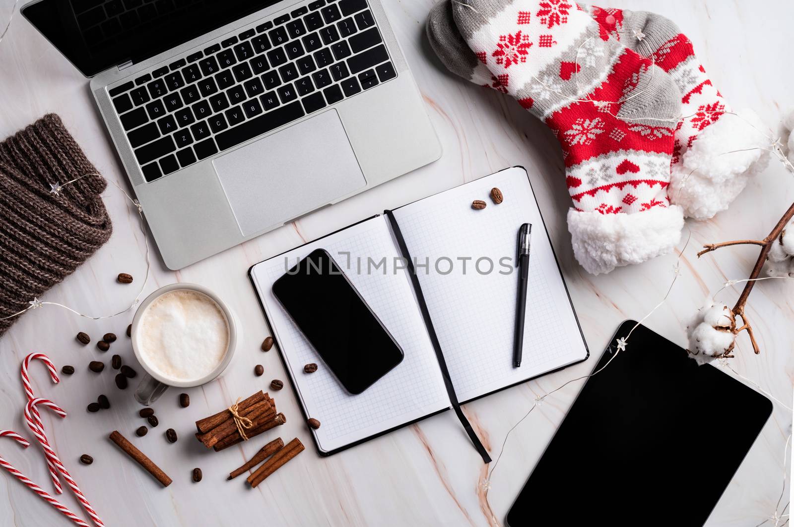 Christmas desktop with laptop, tablet and smart phone surrounded by stockings, candy canes and coffee, top view flat lay, copy space