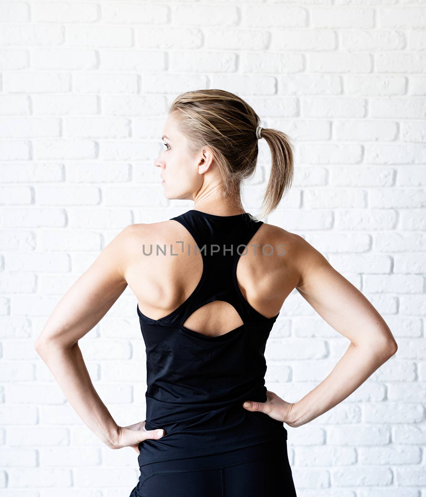 Rear view of an athletic woman in black sportwear by Desperada