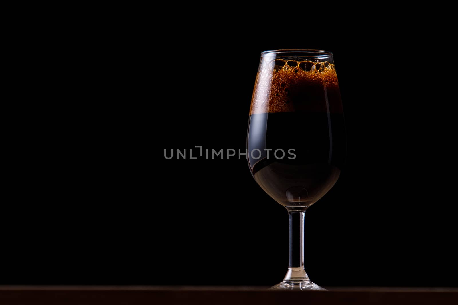 Dark beer in a glass on a dark background