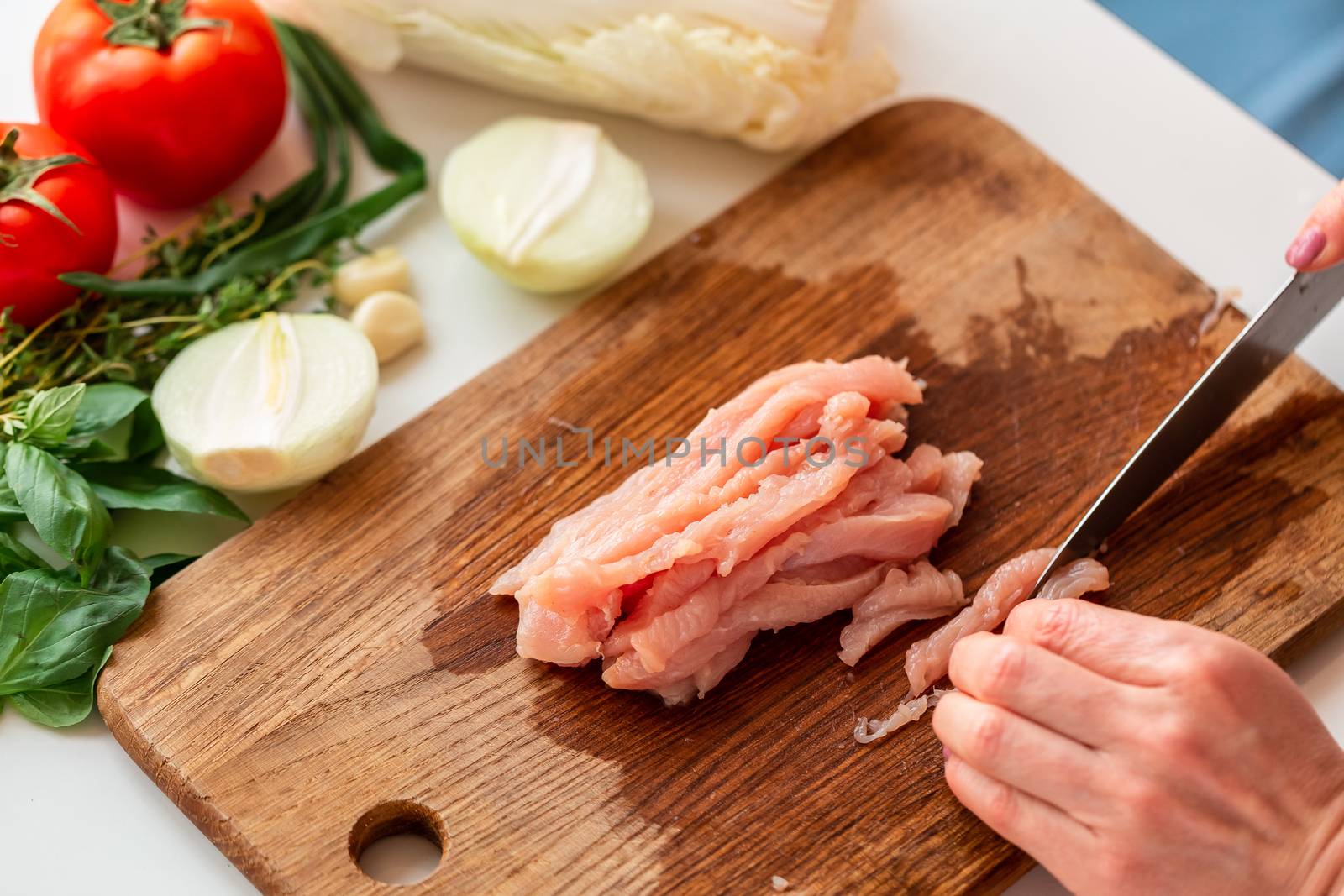 Cooking chicken tenders at home. Cutting chicken fillet on the wooden board for the dish. How to cook cabbage rolls instructions.