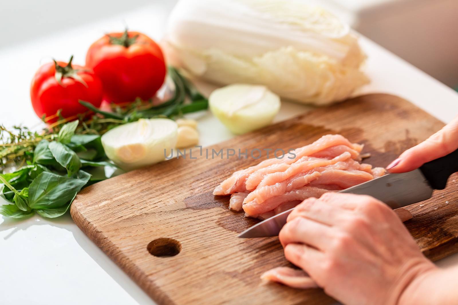 Cooking chicken tenders at home. Cutting chicken fillet on the wooden board for the dish. How to cook cabbage rolls instructions.