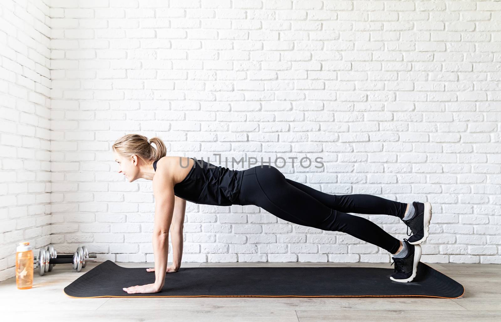 Healthy lifestyle. Sport and fitness. Young fit woman in black sportswear doing push ups at home