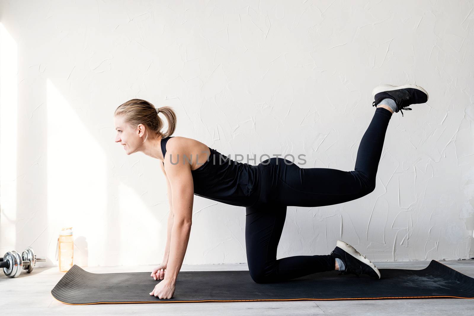 Young blond woman working out doing glutes exercises by Desperada