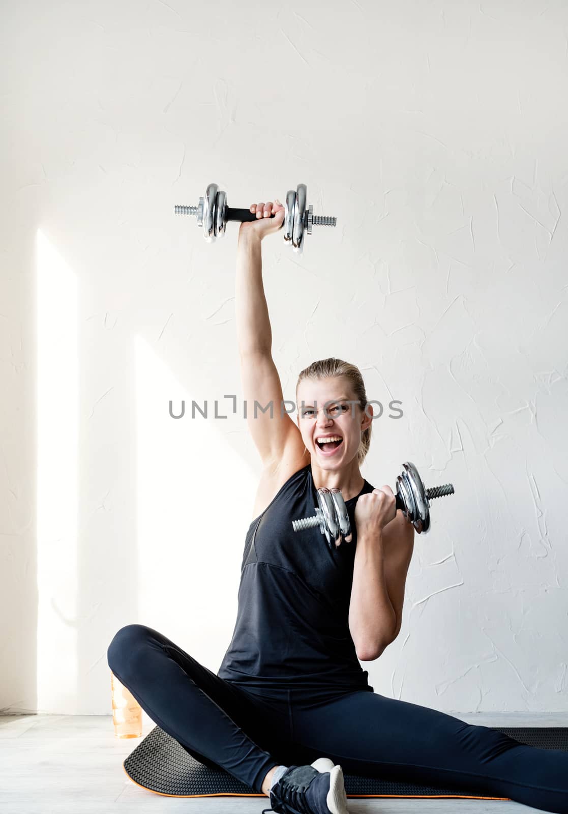 Young blond woman working out with dumbbells by Desperada