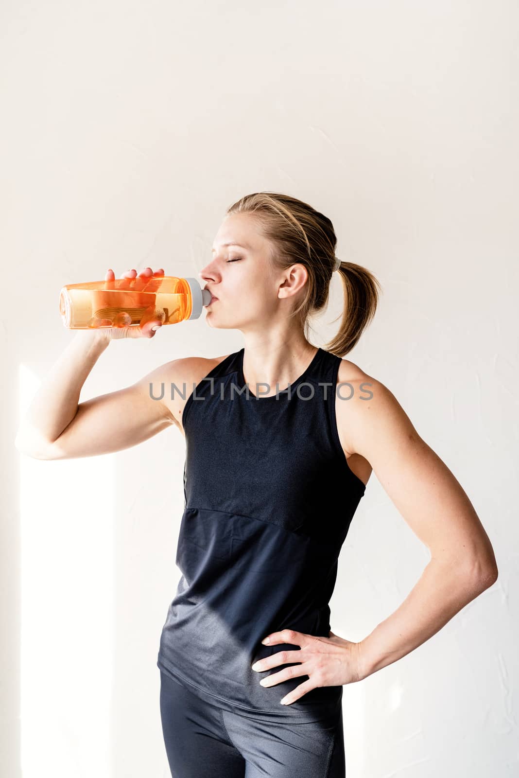 Healthy lifestyle. Sport and fitness. Young blond woman drinking water after workout