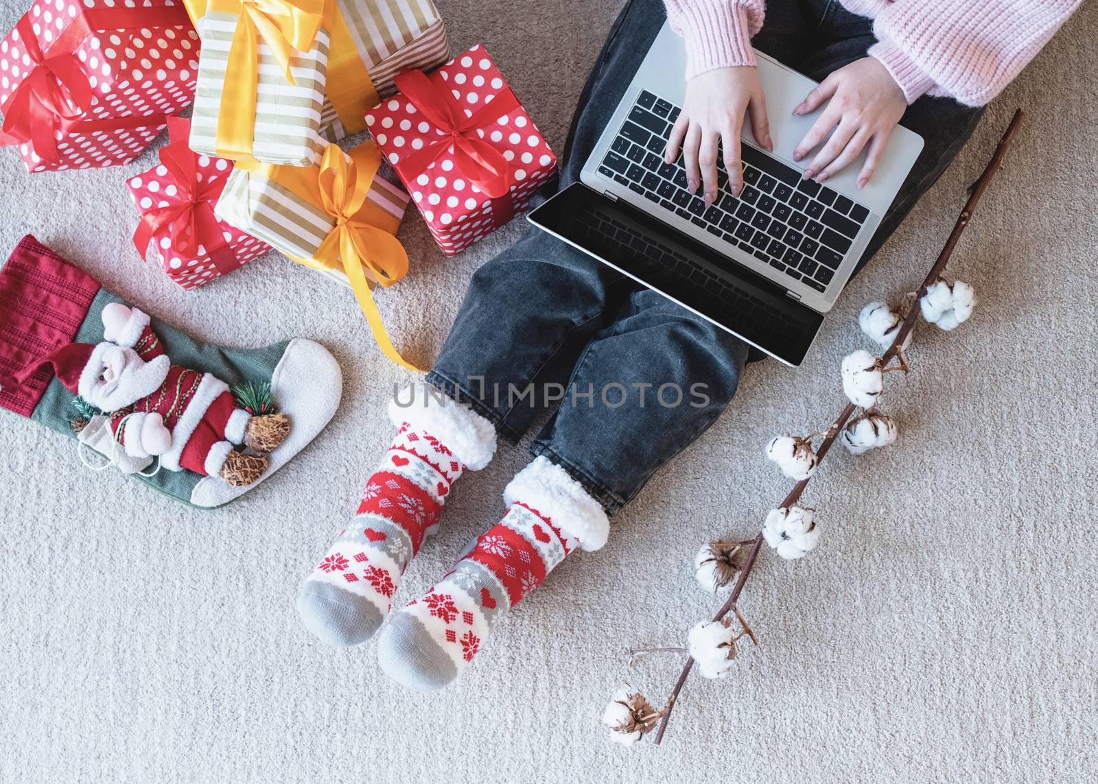 Christmas planing, online shopping concept. Young woman in santa hat shopping online surrounded by presents top view flat lay