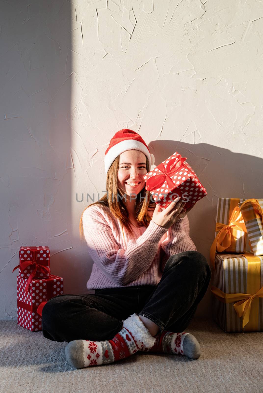 Christmas and New Year. Young woman in santa hat surrounded by presents