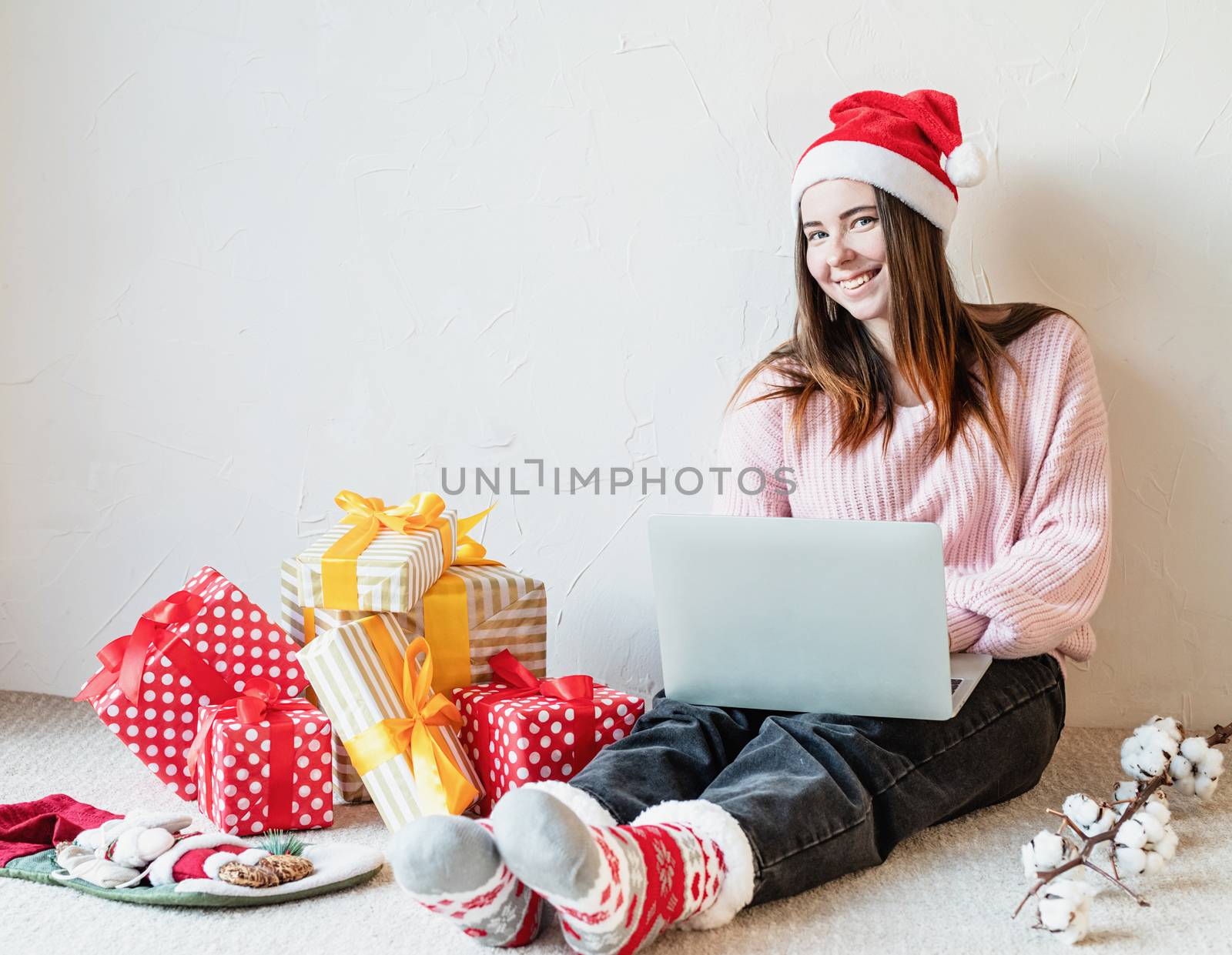 Christmas planing, online shopping concept. Young woman in santa hat shopping online surrounded by presents