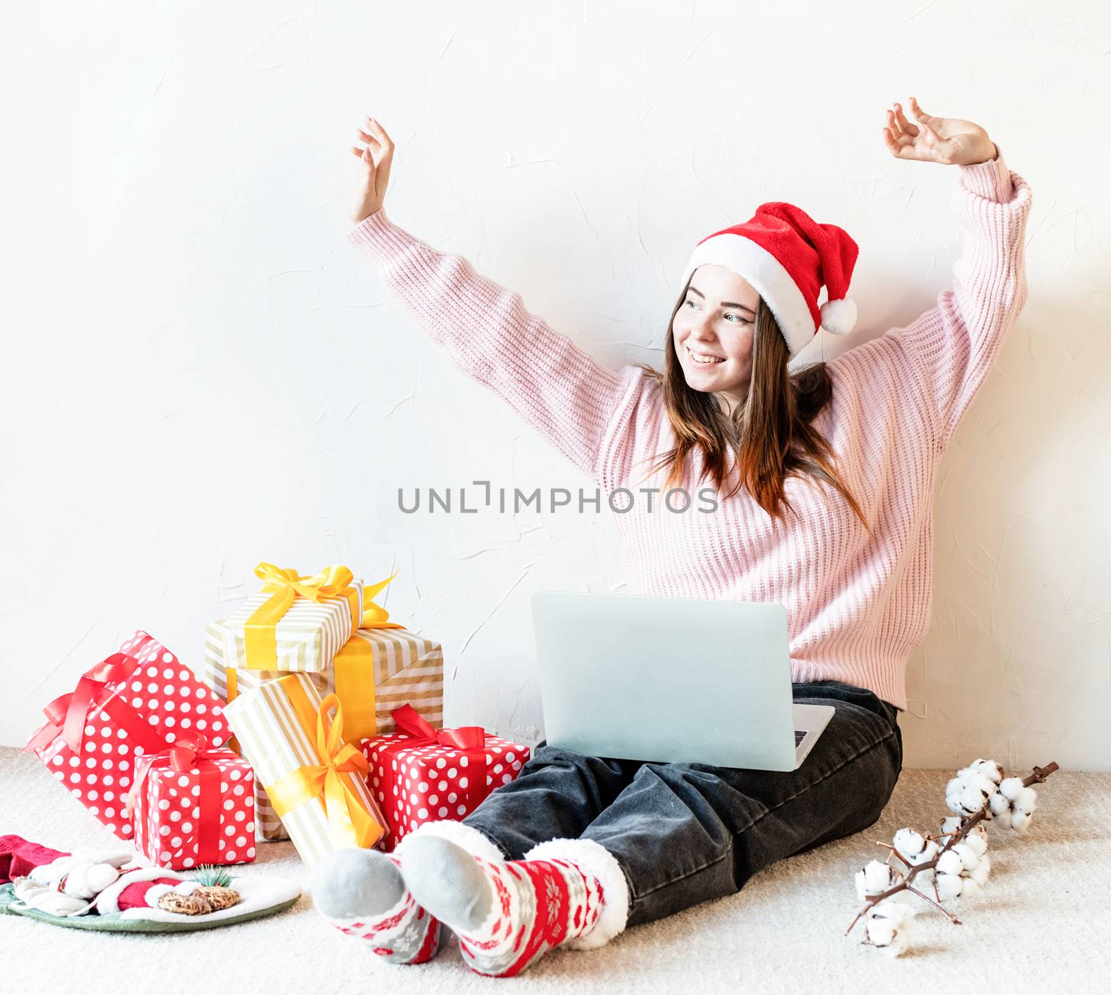 Young woman in santa hat shopping online surrounded by presents by Desperada