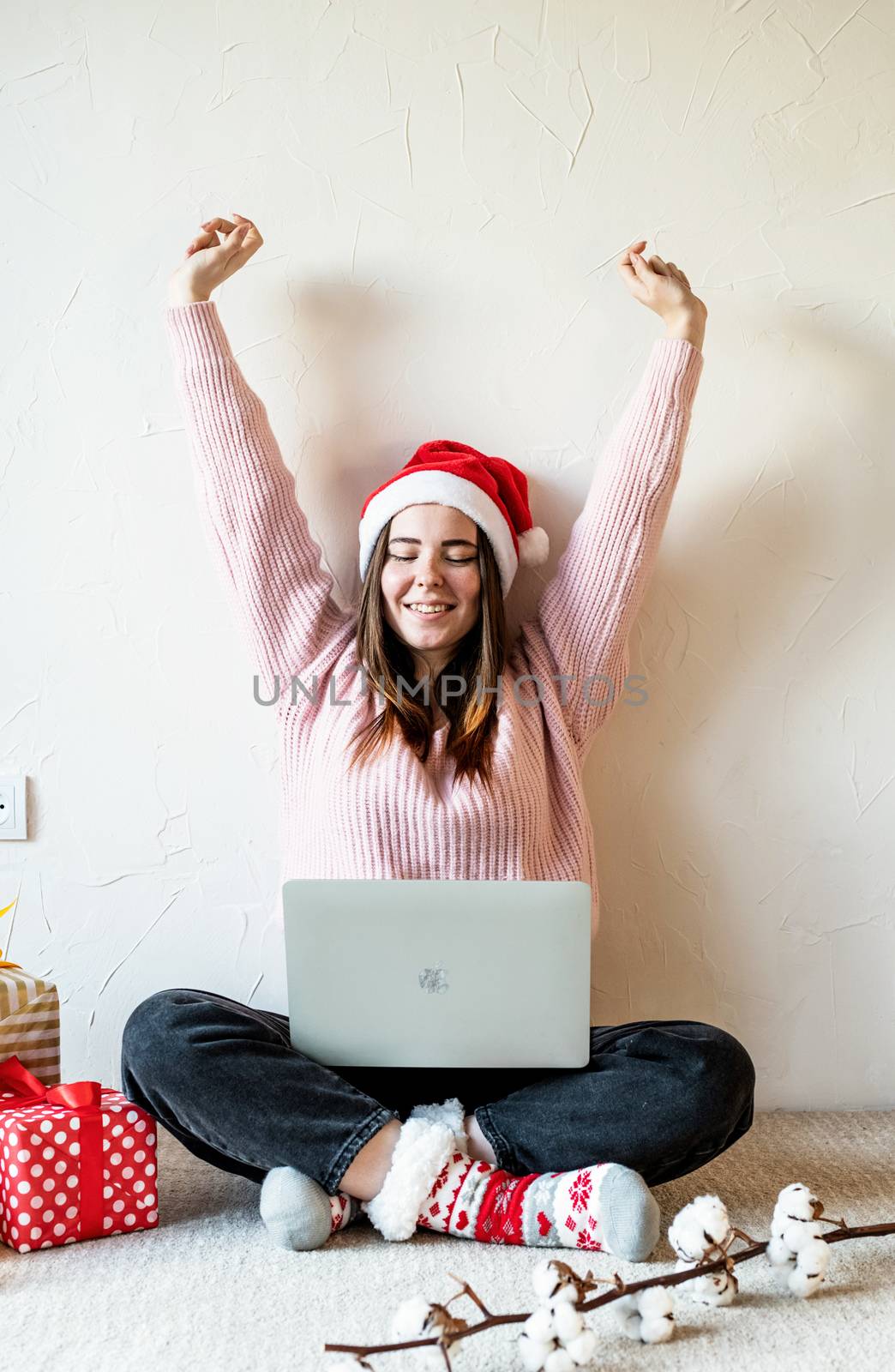 Young woman in santa hat shopping online surrounded by presents by Desperada