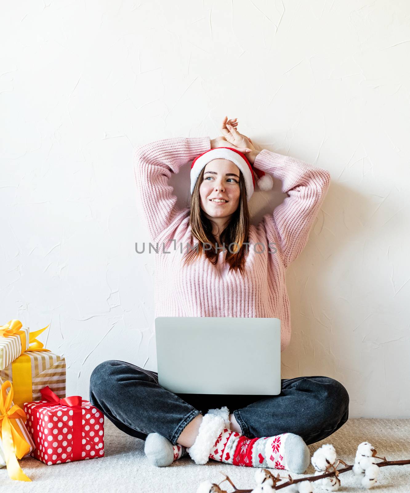 Christmas planing, online shopping concept. Young woman in santa hat shopping online surrounded by presents