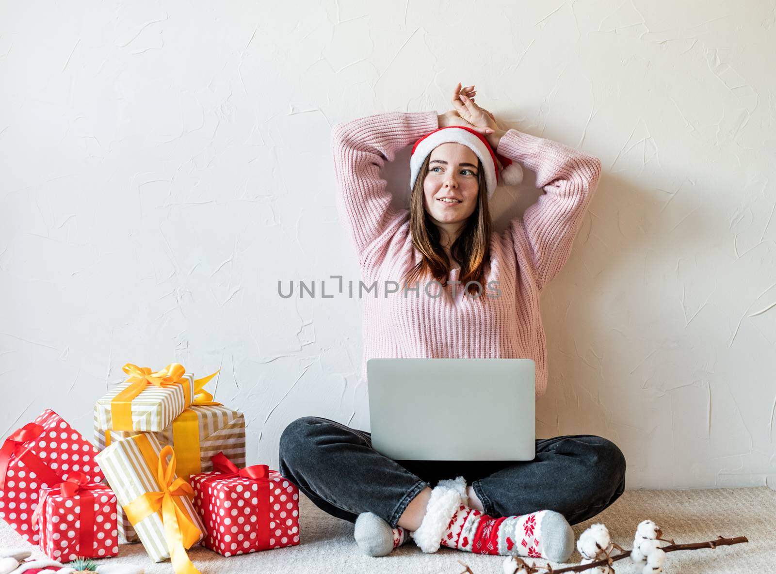Christmas planing, online shopping concept. Young woman in santa hat shopping online surrounded by presents