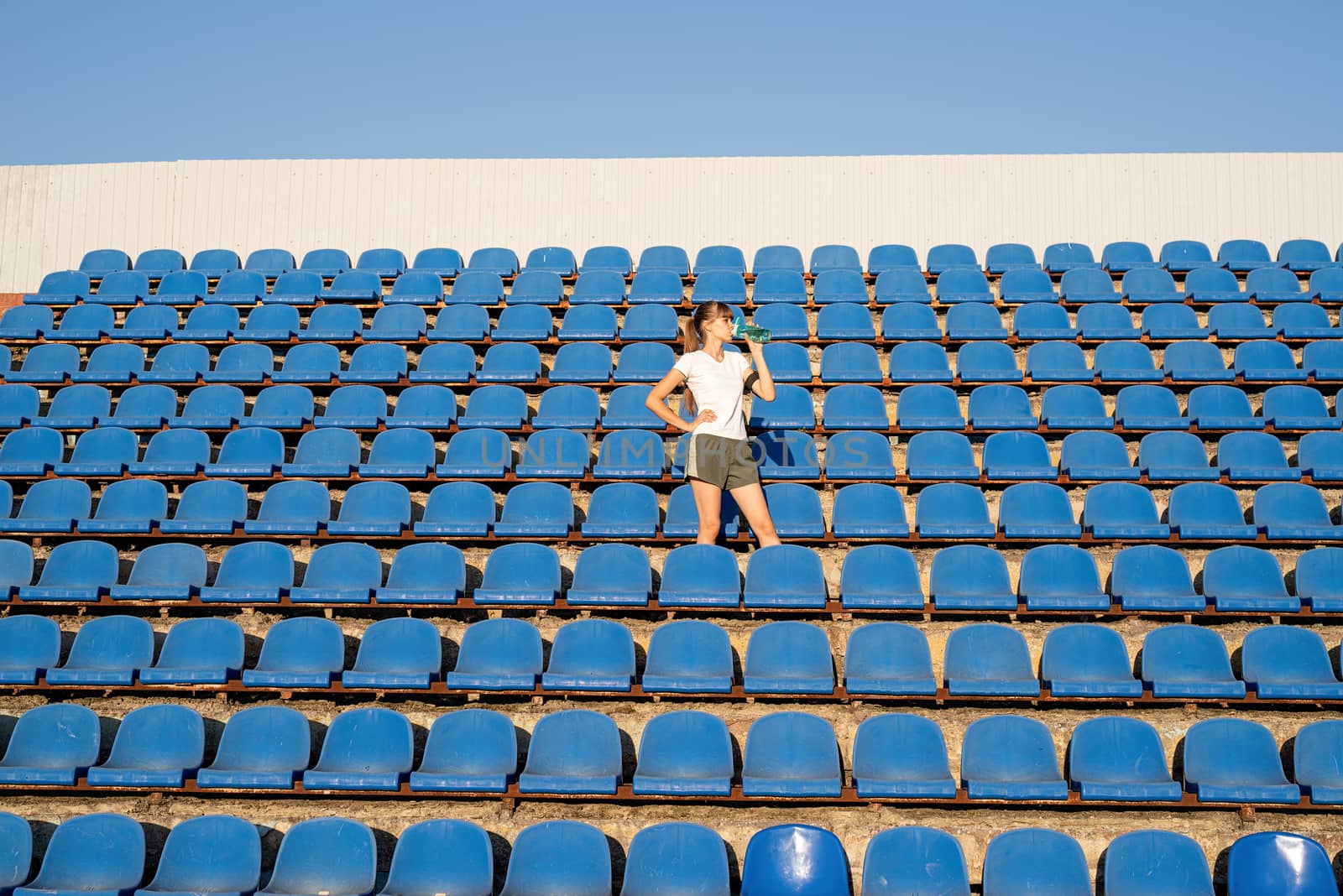 Teenage doing sports alone at the empty stadium by Desperada