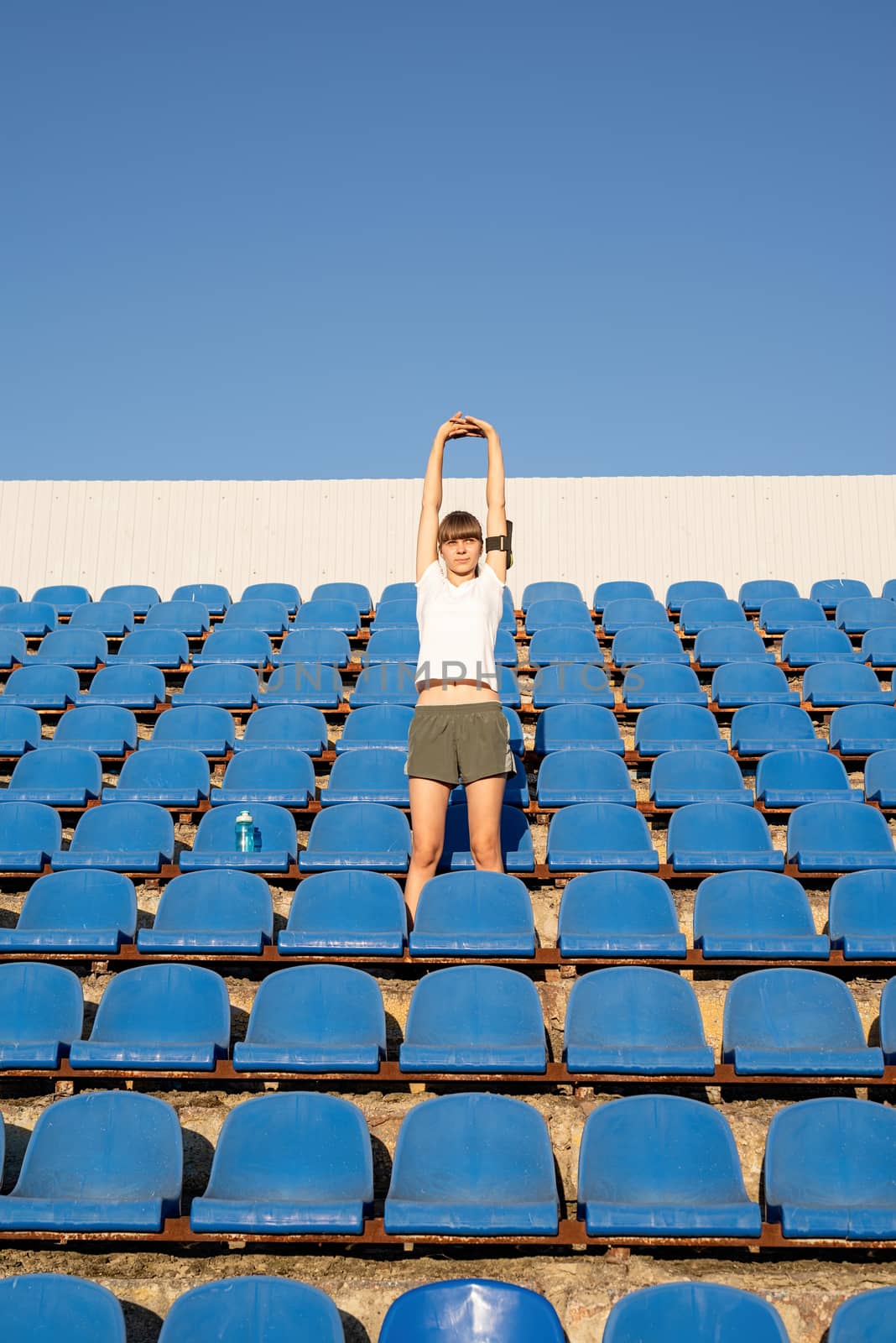 Teenage doing sports alone at the empty stadium by Desperada