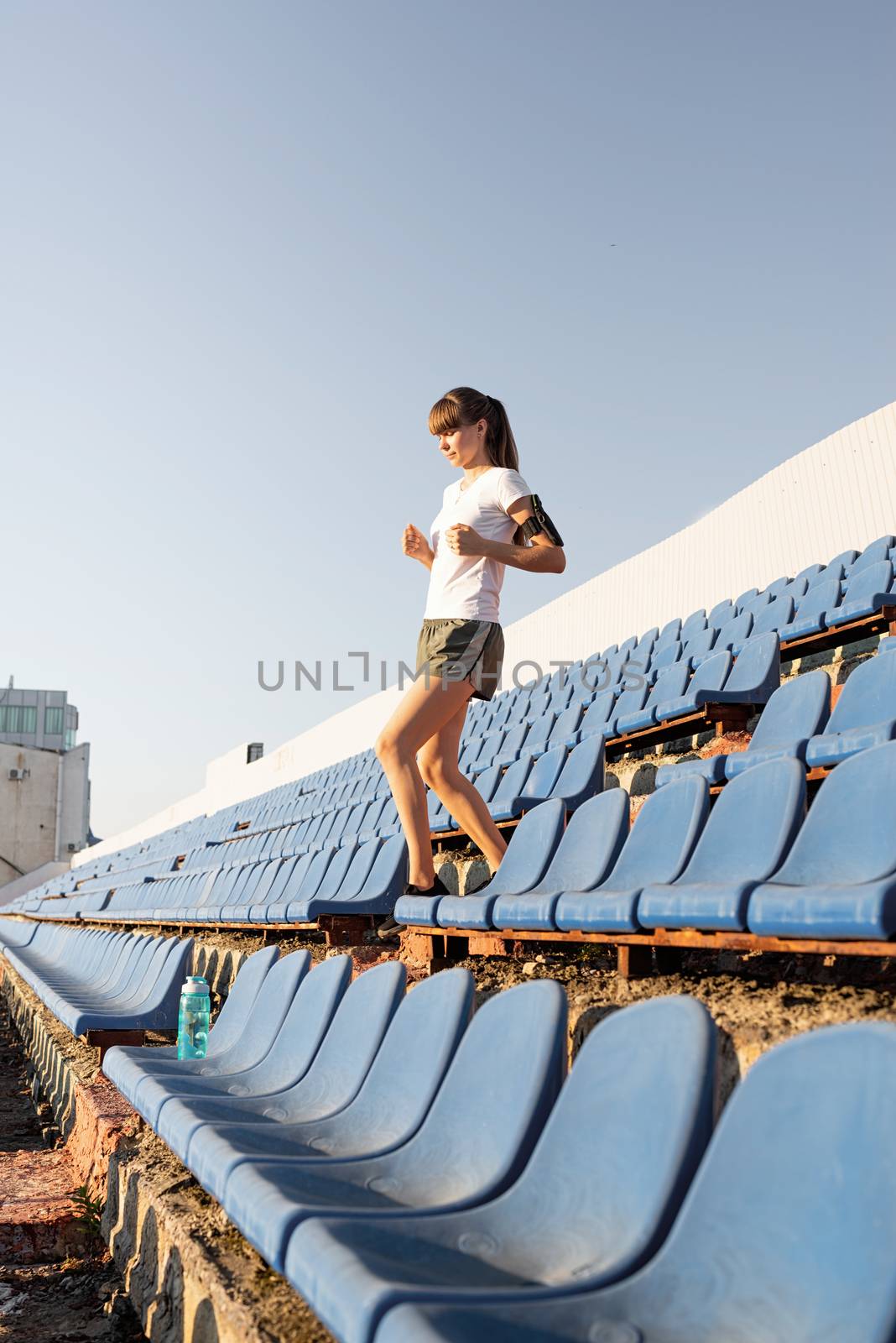 Teenager girl working out at the staduim running down the stairs by Desperada