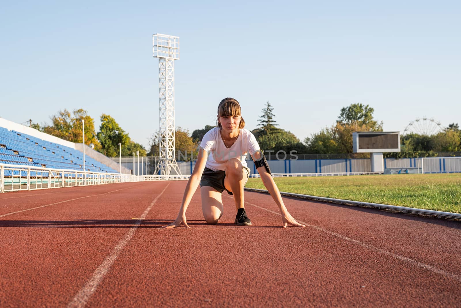 Sports and fitness. Teenager girl getting ready to run at stadium track