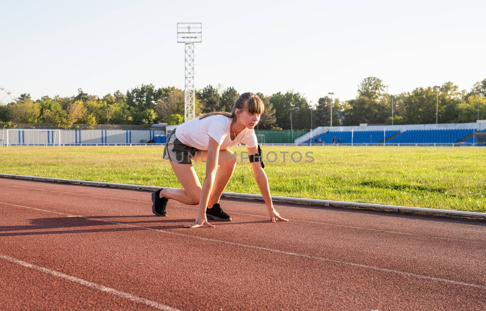 Sports and fitness. Teenager girl getting ready to run at stadium track