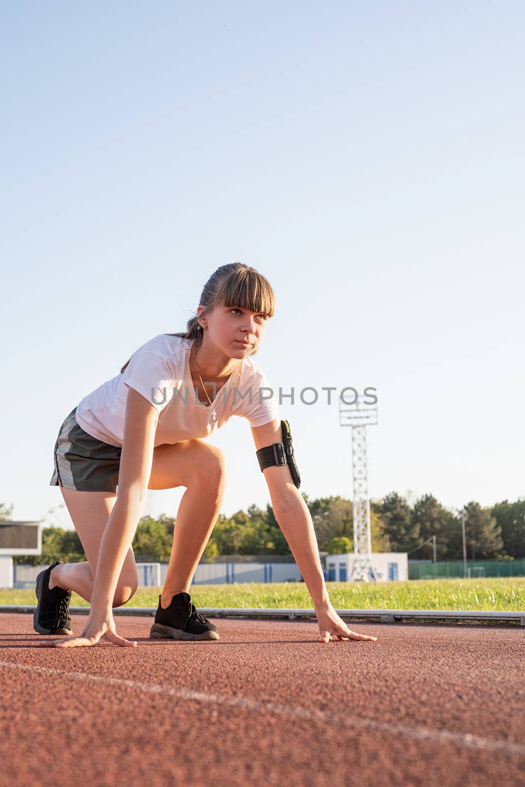 Sports and fitness. Teenager girl getting ready to run at stadium track