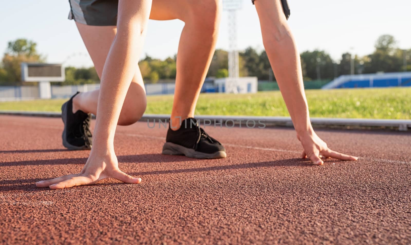 Sports and fitness. Teenager girl getting ready to run at stadium track