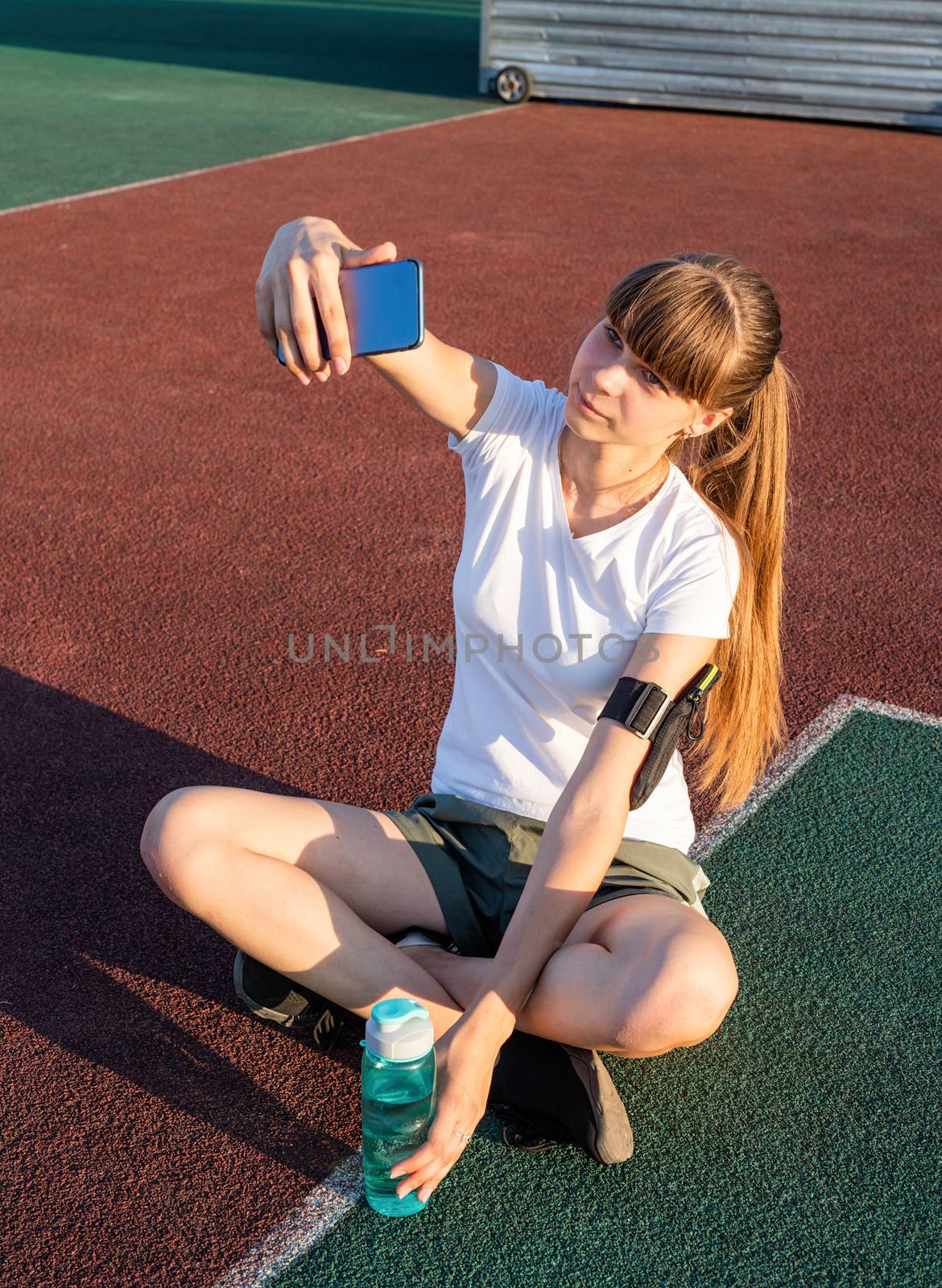 Teen girl making selfie at the stadium after workout by Desperada