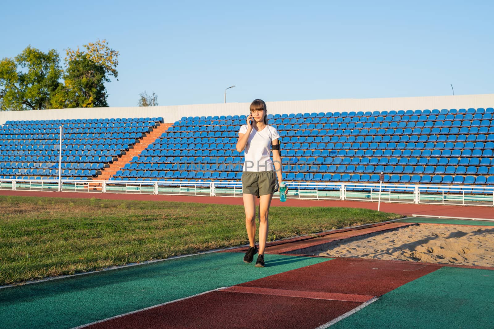 Sports and fitness. Teenager girl talking on the phone at the stadium