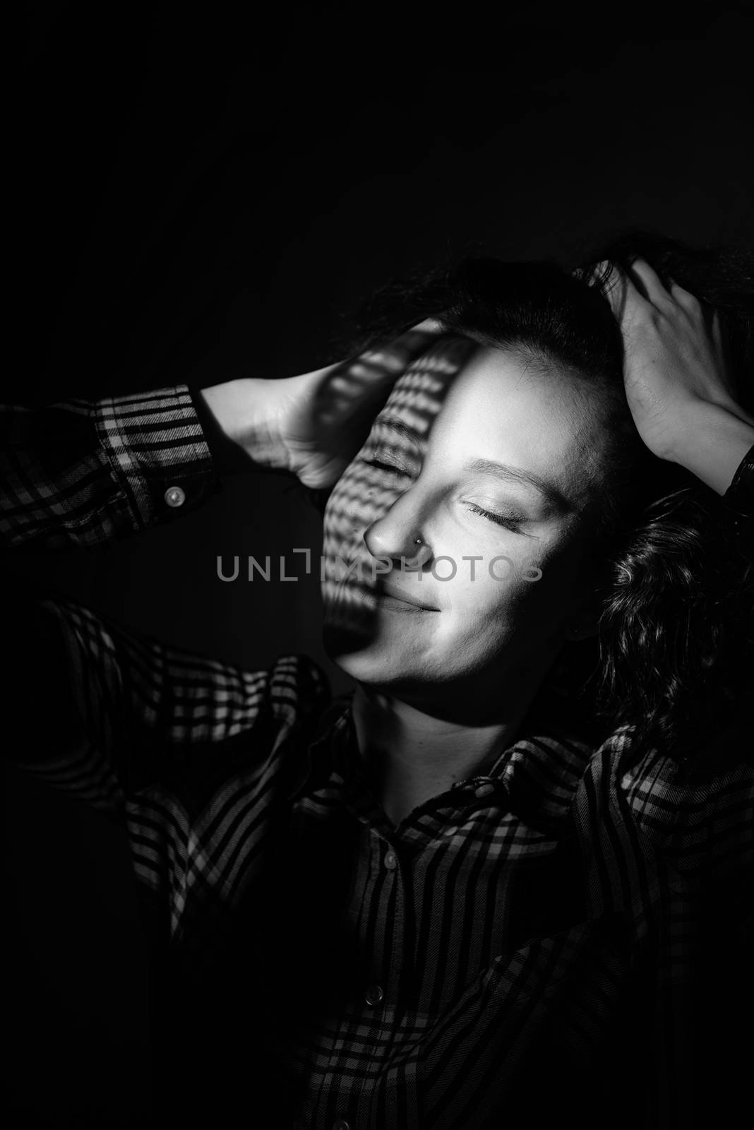 Light and shadow portrait. Beautiful young woman with a creative shadow pattern on the face