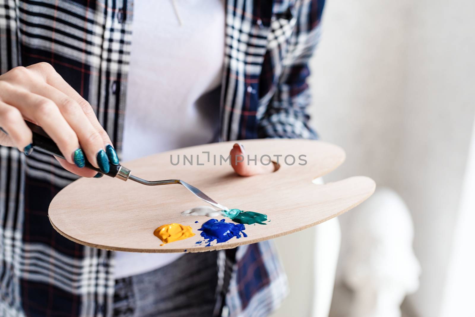 Close up of woman artist hands mixing colors on wooden art palette by Desperada