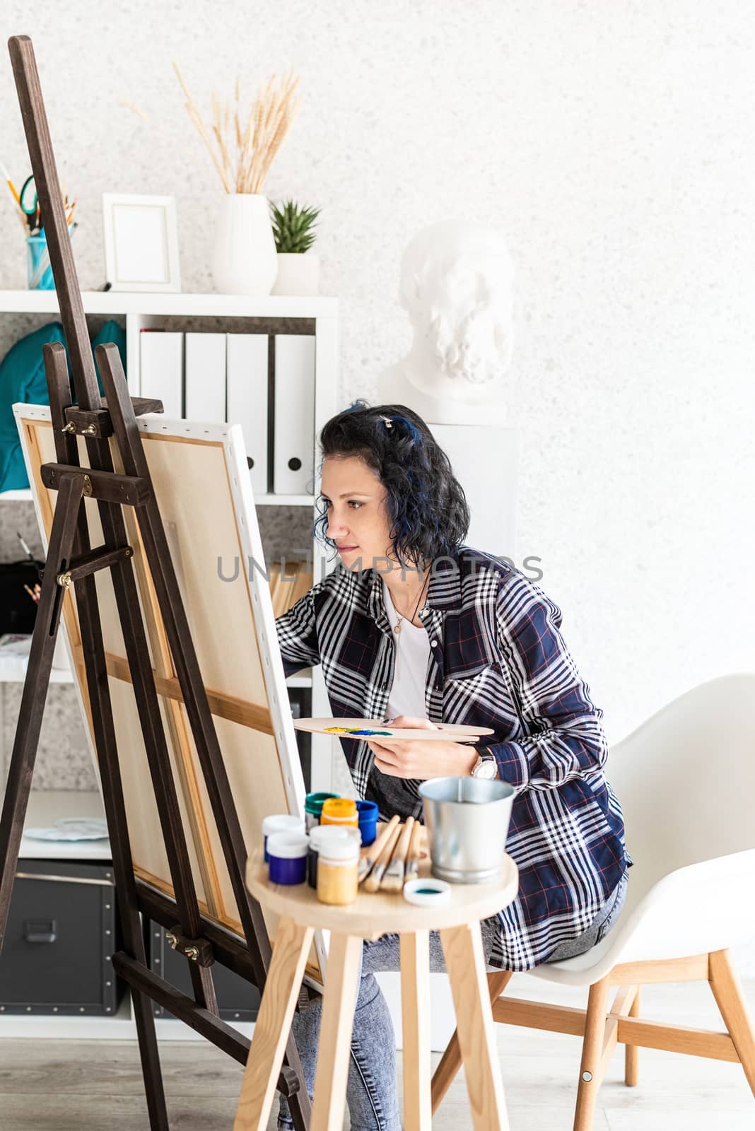 Creative woman with blue dyed hair painting in her studio by Desperada