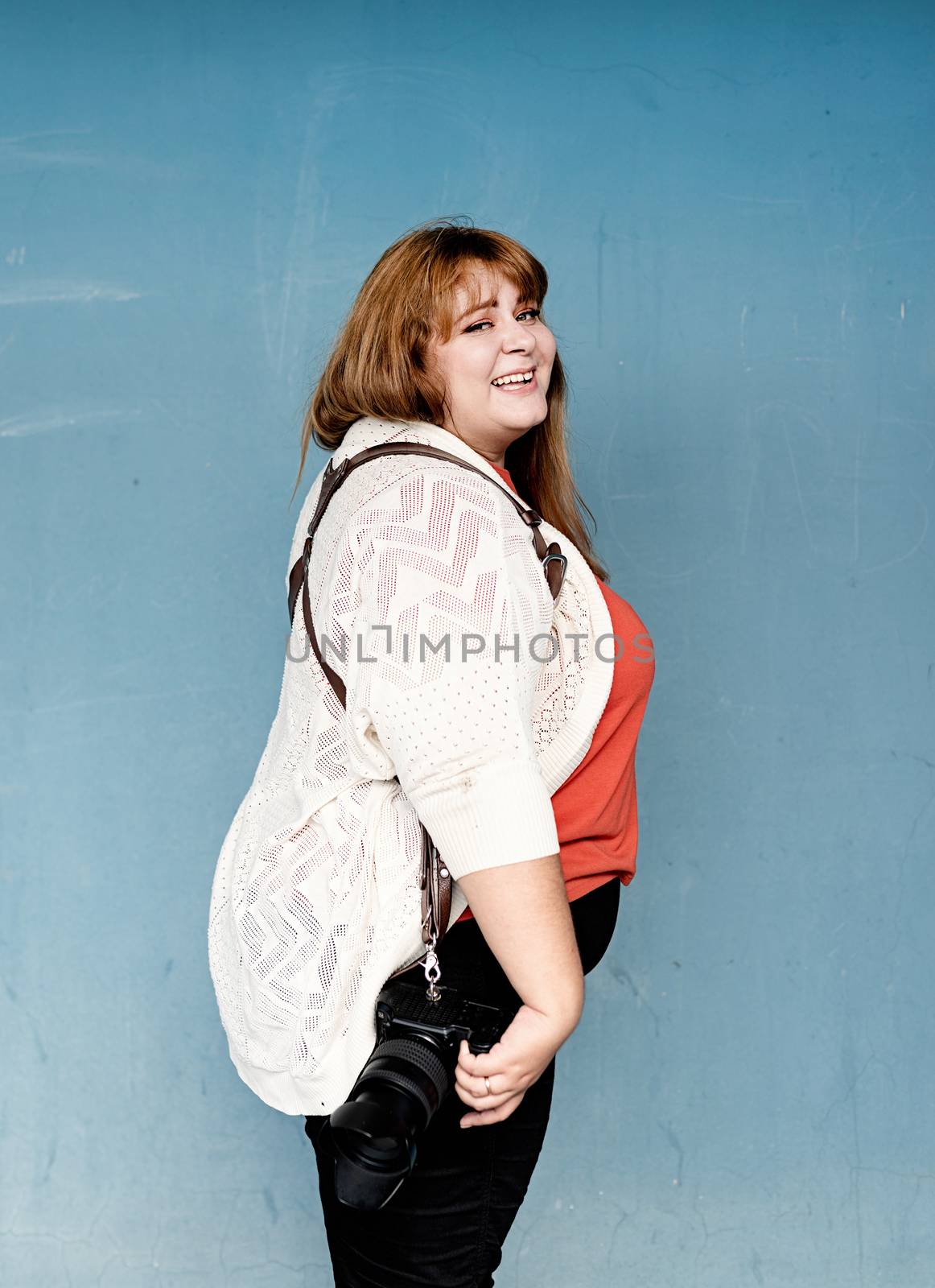Plus size woman photographer outdoors on blue solid background by Desperada