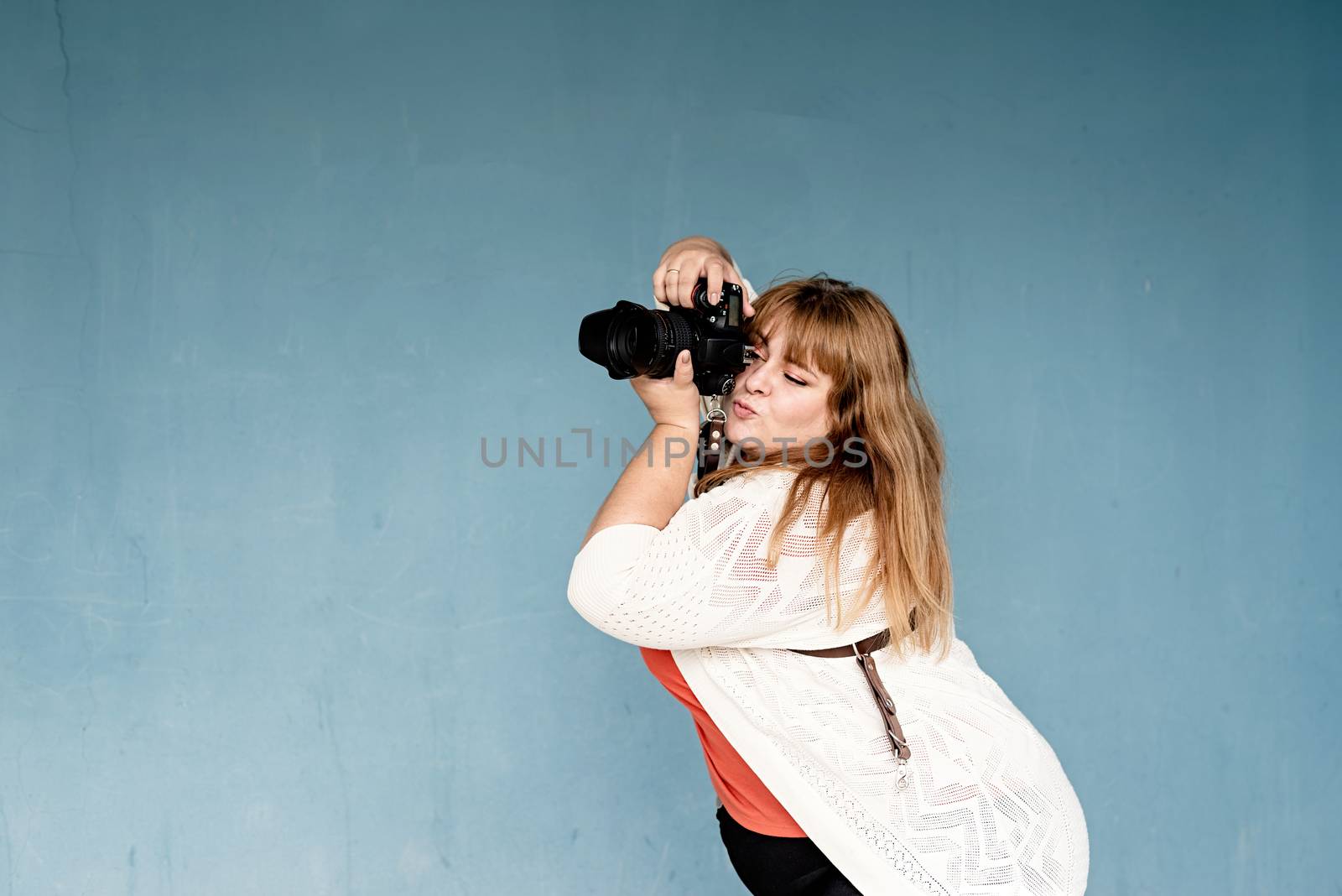 Plus size woman photographer outdoors on blue solid background by Desperada