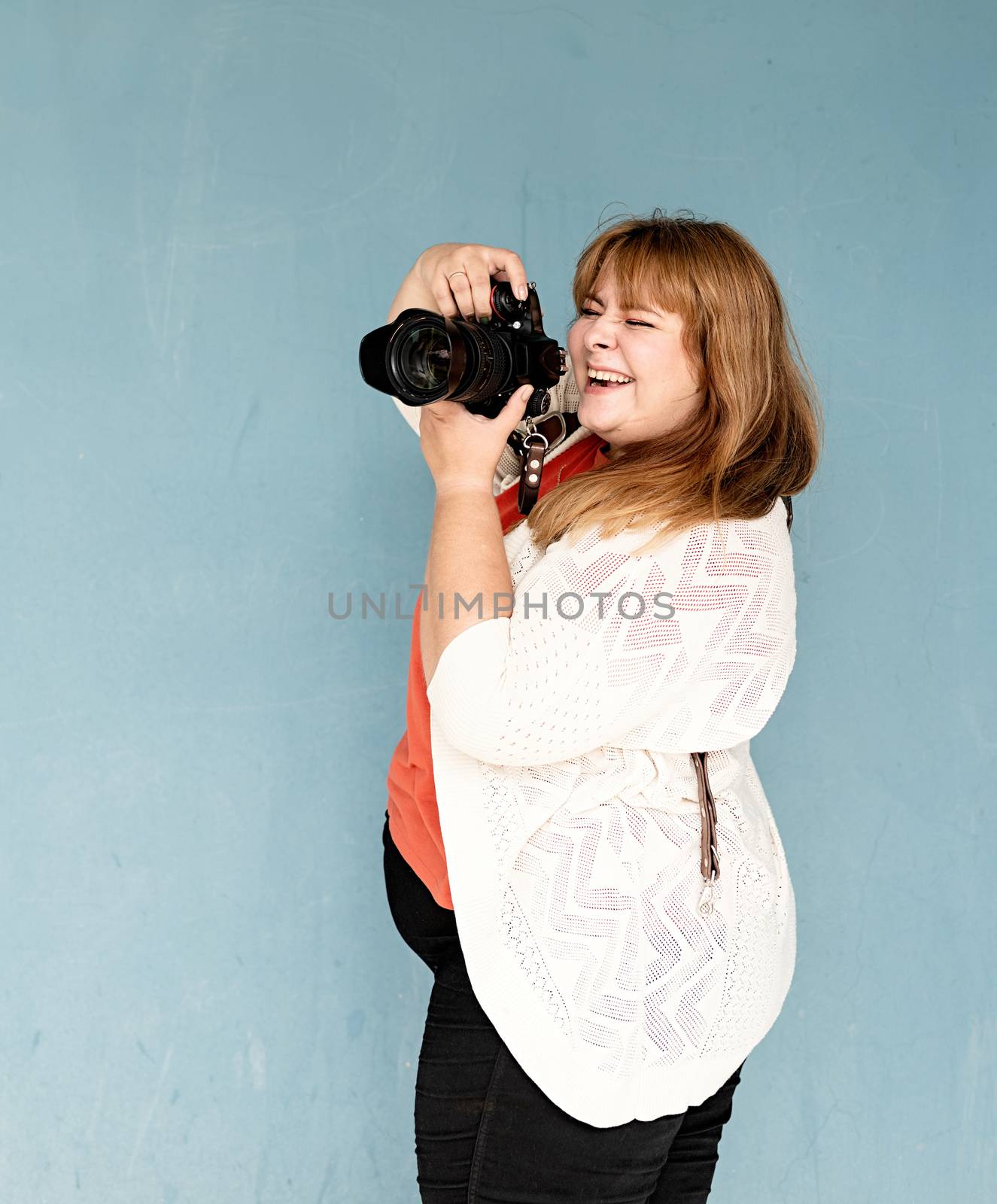 Travel, tourism and entertainment. Plus size woman photographer outdoors on blue solid background