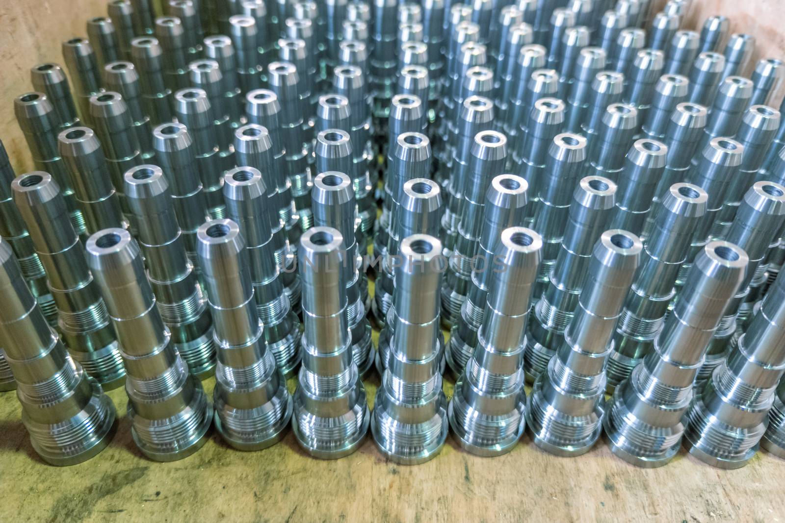Shiny long steel parts background, clean steel threaded rods after fine cnc turning. Standing vertically in a rows with selective focus in directly above perspective.