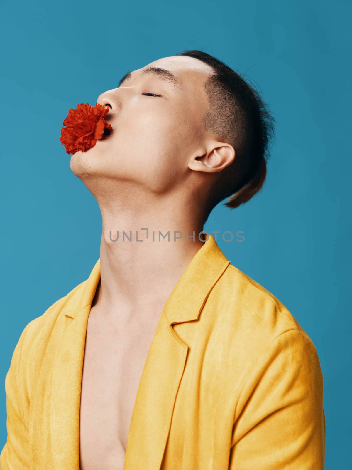 A handsome Asian man with a red flower in his mouth tilted his head back side view Copy Space close-up. High quality photo