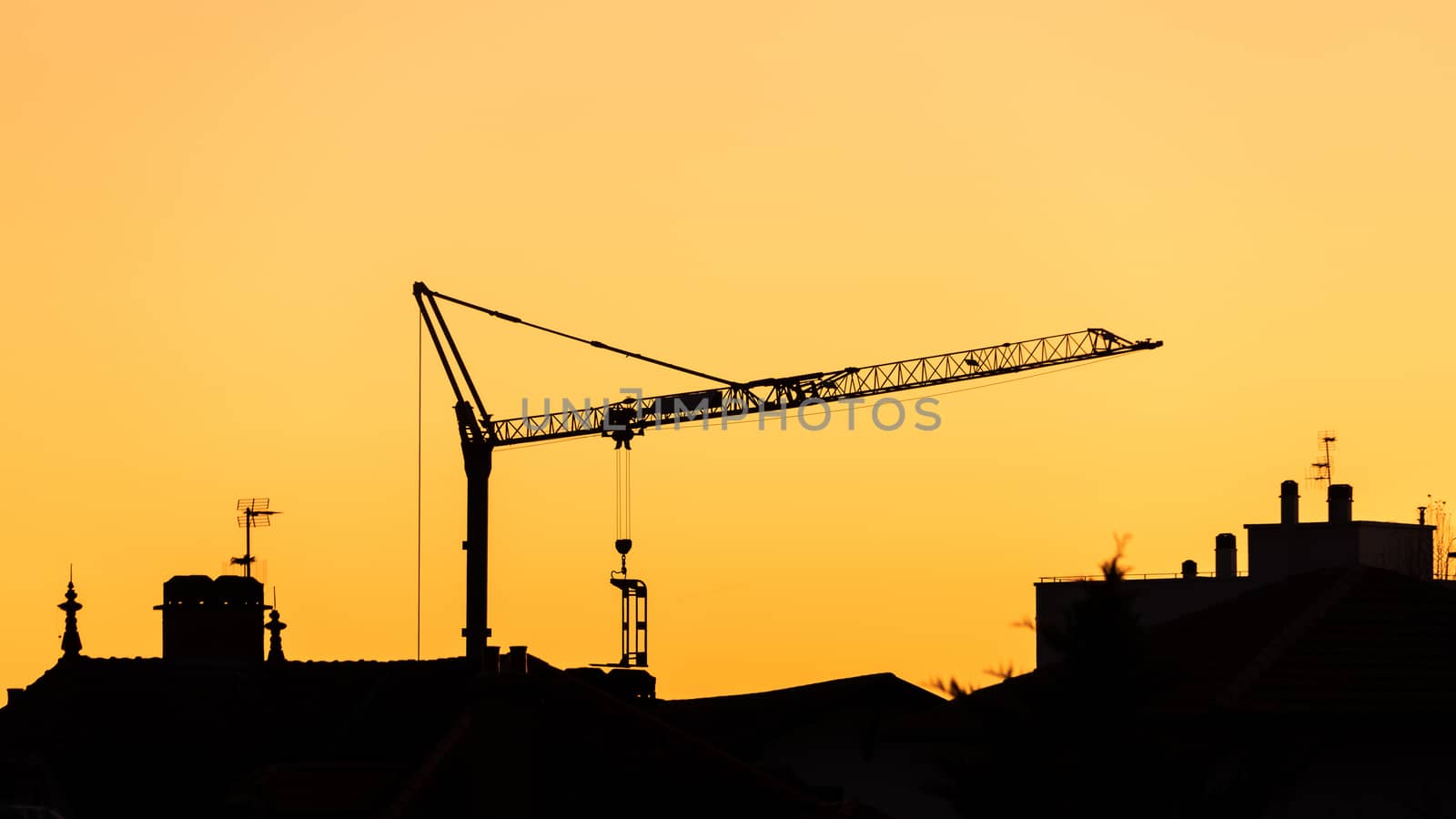 Small construction crane silhouette at sunset