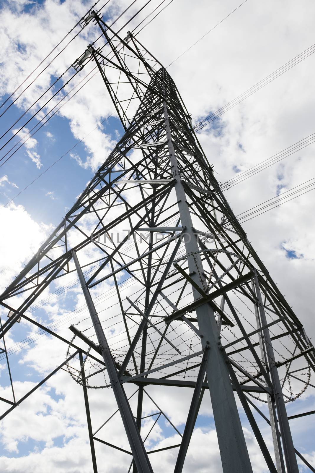 Close up vertical image of the corner of a tall metal electrical transfer tower pylon. Lines of the lattice work converge towards the top. Full frame